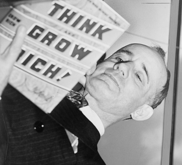 Napoleon Hill en 1937 sosteniendo un ejemplar de Think and Grow Rich ante la camara